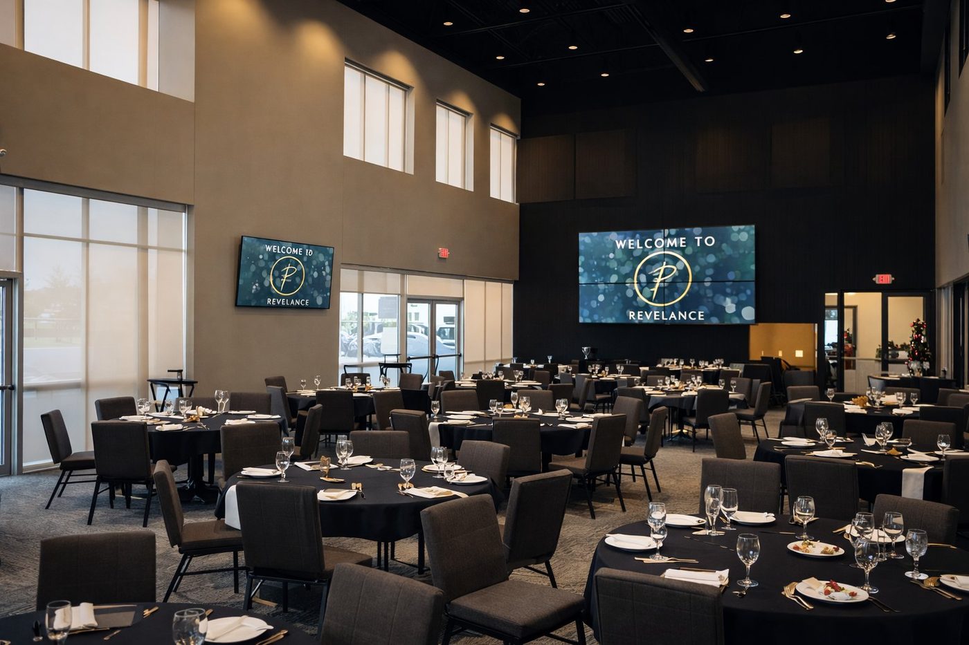 The Revel Room at Revelance — full banquet setup with 25-foot ceilings, video wall, and two-story windows