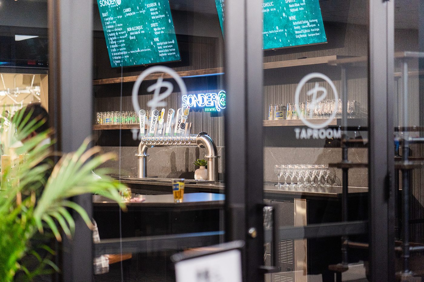 Taproom entry through glass doors with Sonder neon sign