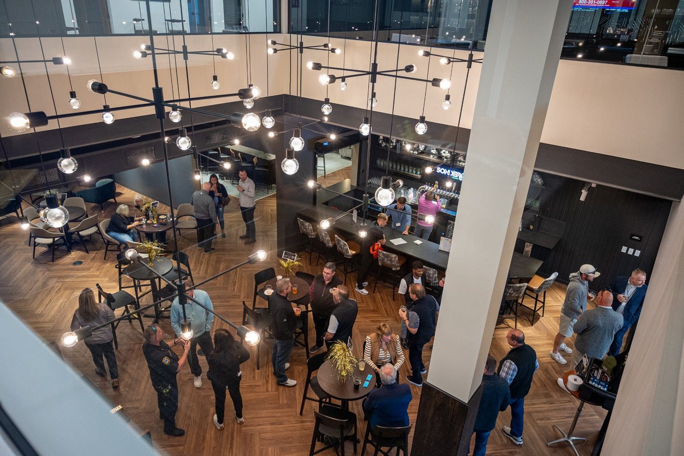 Aerial view of The Taproom at Revelance during a private event — guests mingling under pendant lights with Sonder bar in background
